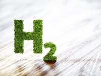1030853_greenhydrogenelementsignonblurredwoodenbackground.3dillustration_591927398_524385