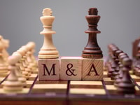 1036285_closeupofkingchesspiecesonwoodenblockswithmergersandacquisitions_599480_crop