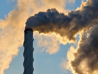 Factory pipe close-up with a lot of smoke against blue sky
