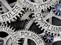 Macro photo of tooth wheels with COMPLIANCE, REGULATIONS, STANDARDS, POLICIES and RULES words imprinted on metal surface
