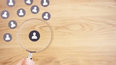 Human resources management and recruitment concept, Hand holding magnifying glass search people paper icon on top desk._1124554700