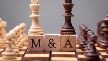 1036285_closeupofkingchesspiecesonwoodenblockswithmergersandacquisitions_599480_crop