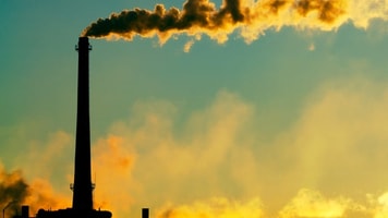 CO2 Steam rises smokestack factory silhouetted against sunlight