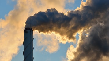Factory pipe close-up with a lot of smoke against blue sky