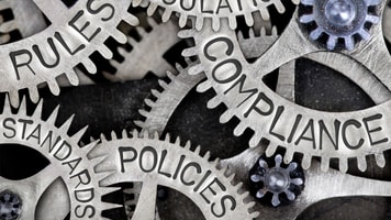 Macro photo of tooth wheels with COMPLIANCE, REGULATIONS, STANDARDS, POLICIES and RULES words imprinted on metal surface