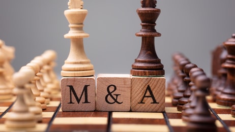1036285_closeupofkingchesspiecesonwoodenblockswithmergersandacquisitions_599480_crop