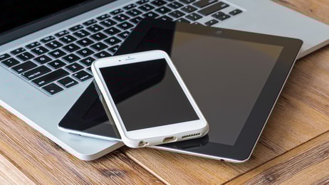 laptop smart phone and a tablet on a wooden table